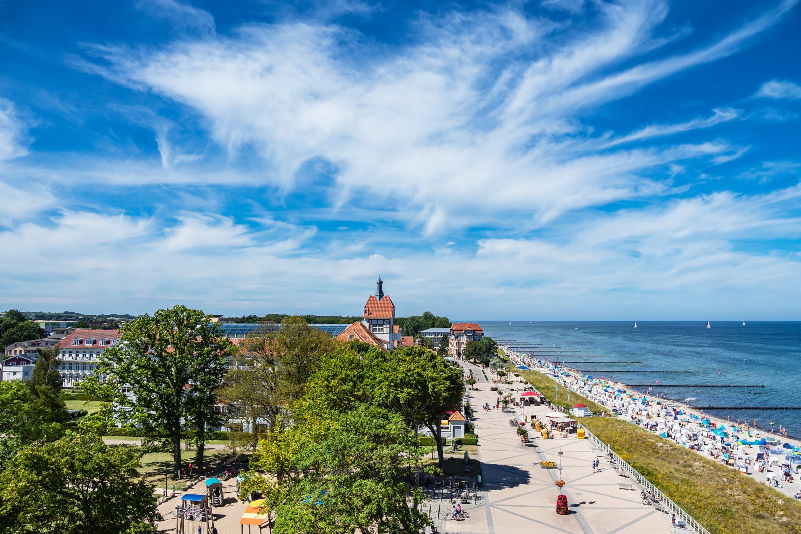 Blick über Kühlungsborn auf Strand und Promenade, im Vordergrund Bäume