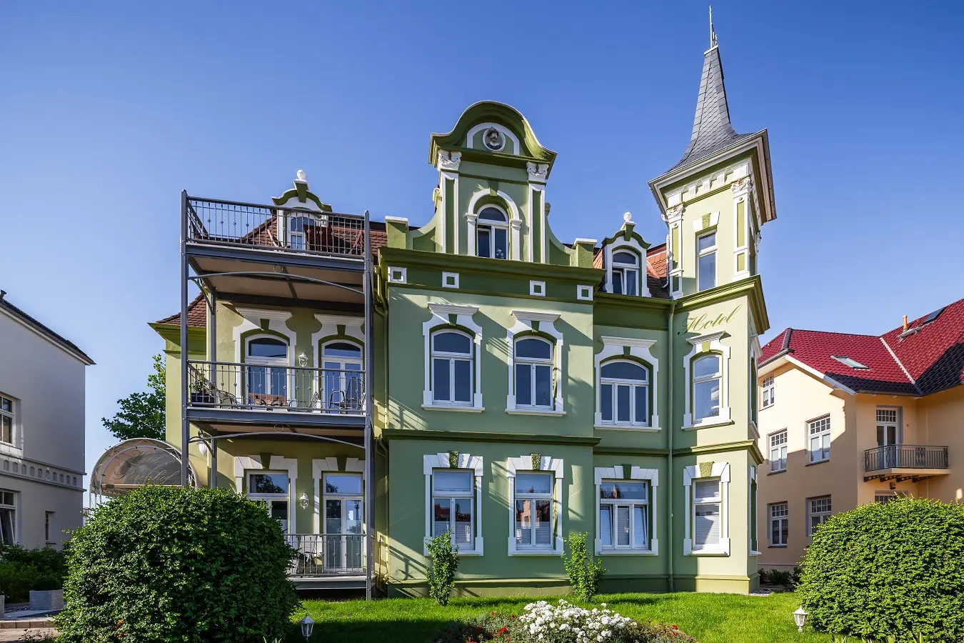Die grüne Jugendstilfassade des Hauses Rosenhof mit Türmchen und Balkonen hinter dem Vorgarten