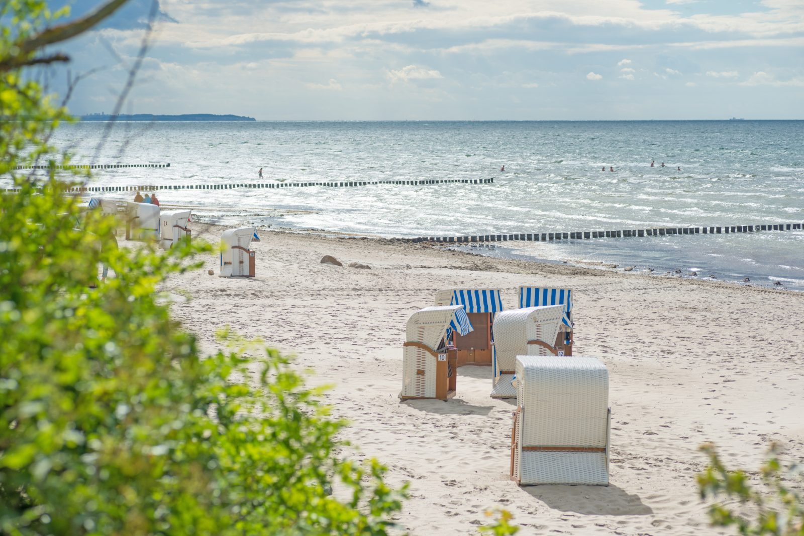 Strandkörbe am Kühlungsborner Strand, im Wasser stehen Buhnen